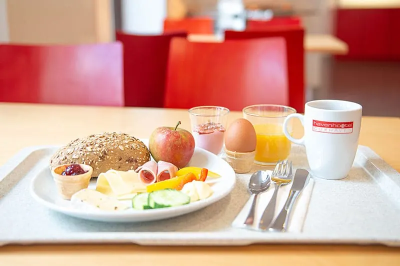 Frühstückstablett mit Brötchen, Ei, Obst und Kaffee