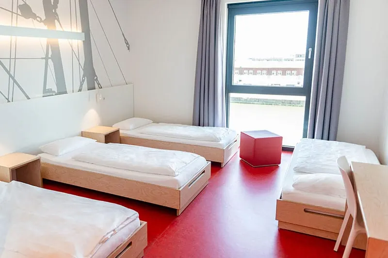 4-Bett-Zimmer mit Einzelbetten und rotem Boden